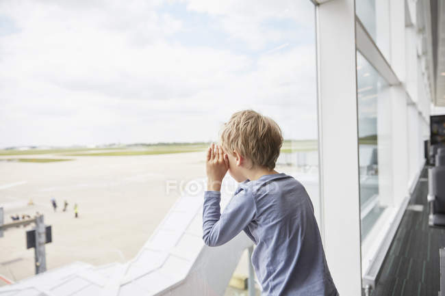 Junge blickt aus Flughafenfenster auf Landebahn — Stockfoto