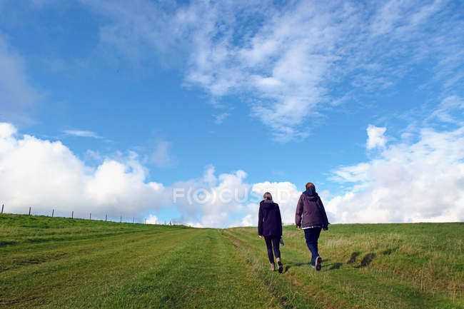 Mother and daughter walking in field, rear view, South Downs, East Sussex, UK — Stock Photo