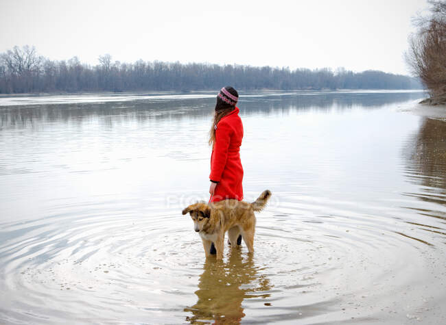 Mujer joven en el río con perro en ondulaciones - foto de stock