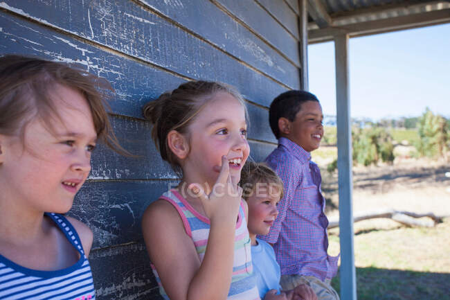 Four children outside clapboard cabin — Stock Photo