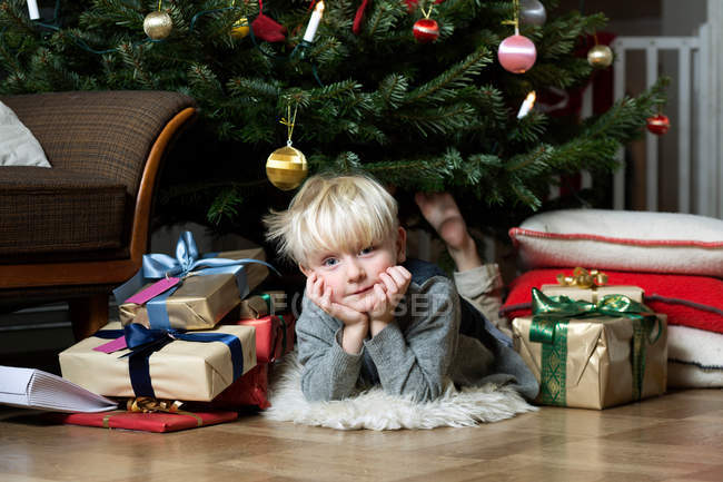 Menino que coloca sob a árvore de Natal — Fotografia de Stock
