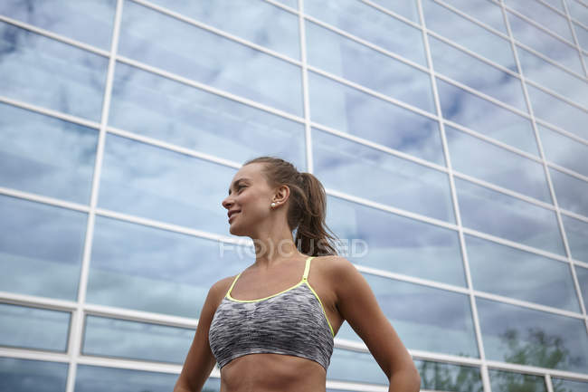 Junge Frau beim Training, steht vor Bürogebäude — Stockfoto