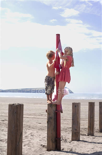 Brother and sister standing on groyne on beach — Stock Photo