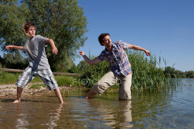 Père et fils sautant des rochers sur le lac — Photo de stock