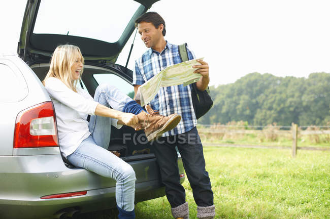 Couple en voiture carte lecture préparation à l'aventure de randonnée — Photo de stock