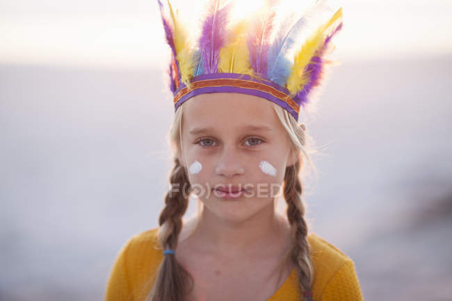 Retrato de menina vestida como nativa americana com penas cobertura para a cabeça — Fotografia de Stock