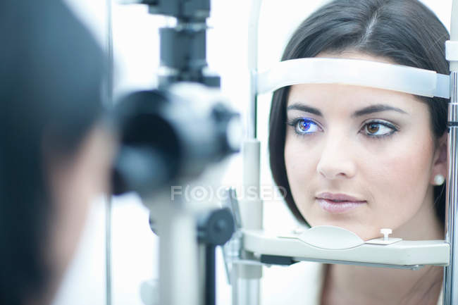 Mujer joven examinándose los ojos - foto de stock