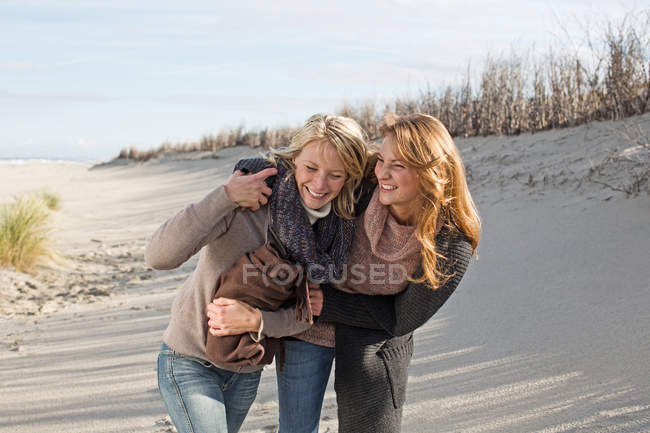 Smiling women walking on beach — Stock Photo