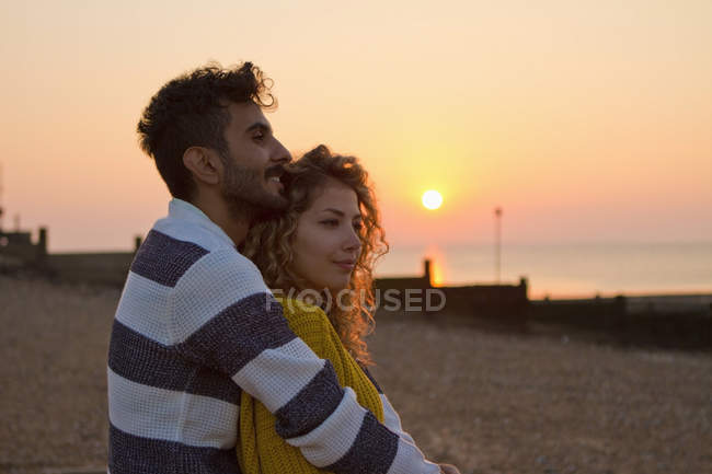 Молода пара на пляжі на заході сонця — стокове фото
