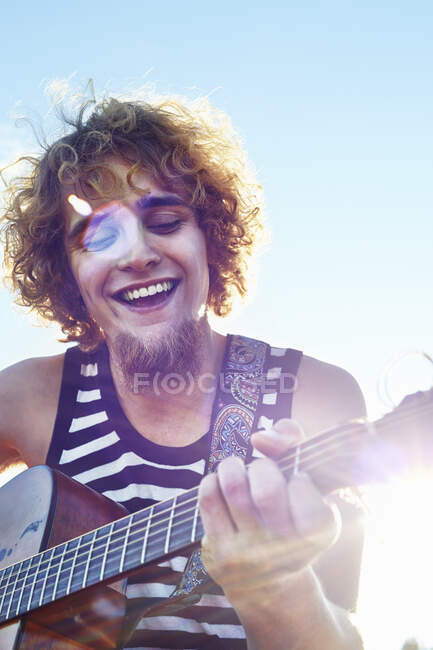 Junger Mann spielt Gitarre im Sonnenschein — Stockfoto