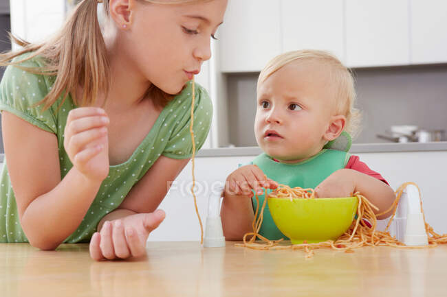 Дівчинка і малюк грають з спагеті — стокове фото