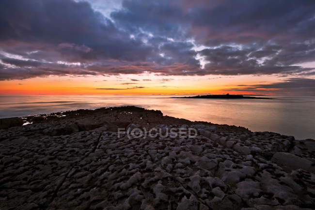 Sole che tramonta sulle formazioni rocciose della spiaggia — Foto stock