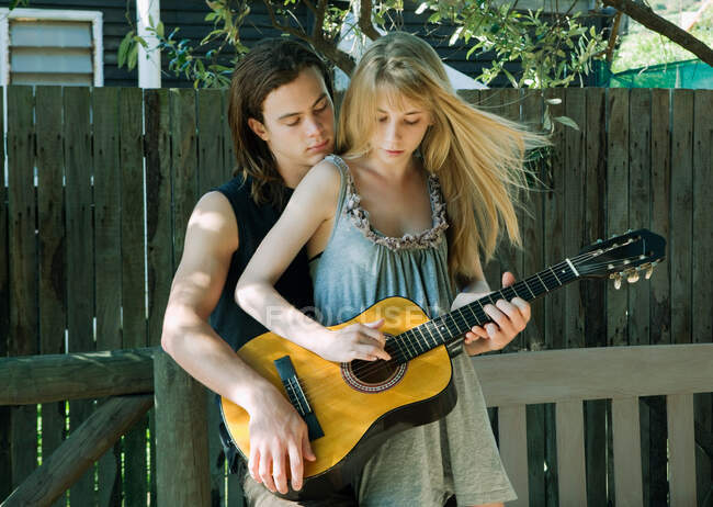 Chica tocando la guitarra con un hombre joven - foto de stock