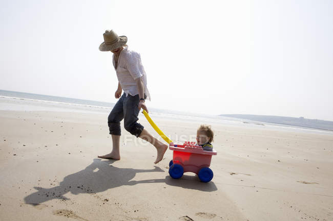 Father with daughter in wagon on beach — Stock Photo