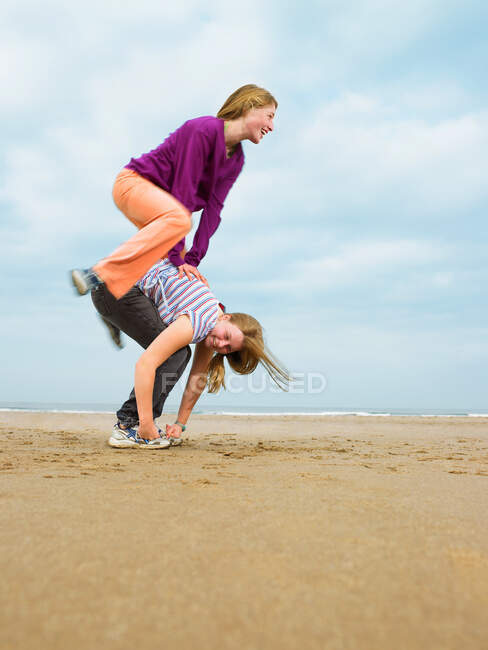 Zwei Weibchen spielen Sprung-Frosch am Strand — Stockfoto