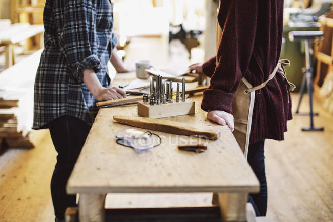 Cropped view of two craftswomen at workbench in pipe organ workshop — Stock Photo