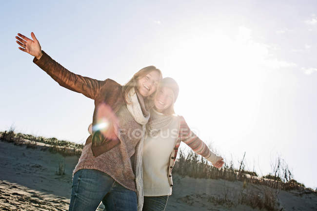 Улыбающиеся женщины, обнимающиеся на пляже — стоковое фото