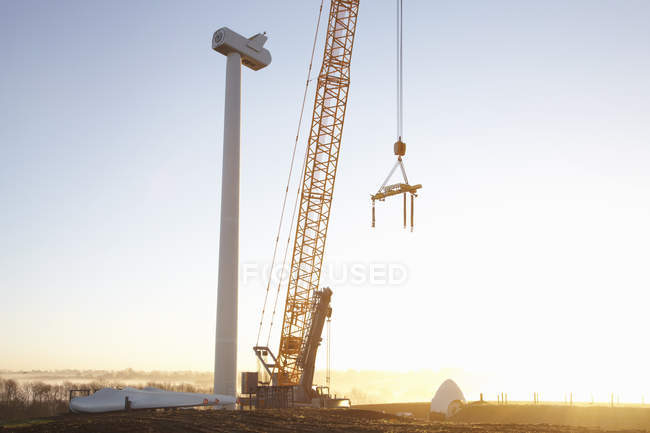 Turbina eólica siendo erigida al atardecer - foto de stock