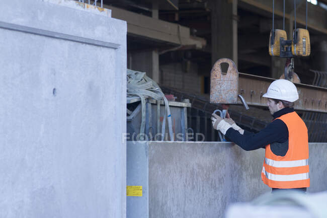 Trabalhador da fábrica anexando corda ao bloco de concreto na fábrica de reforço de concreto — Fotografia de Stock