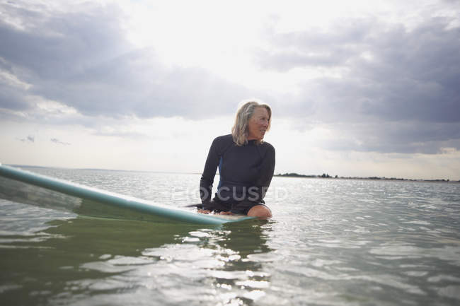 Старша жінка сидить на дошці для серфінгу в морі — стокове фото