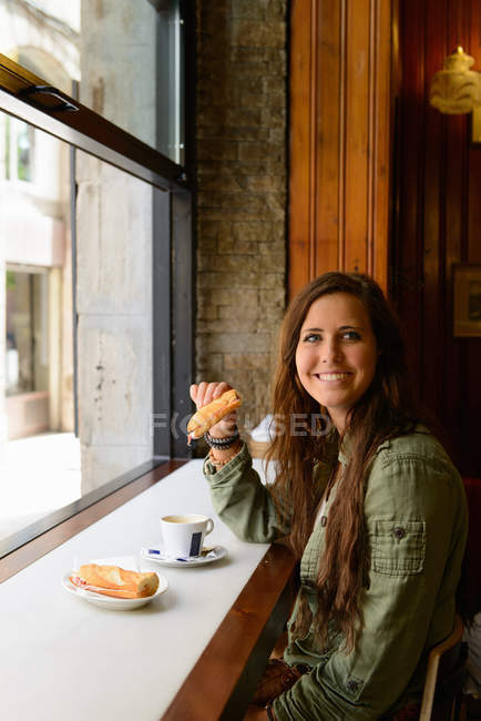 Young female eating sandwich in Barcelona cafe, Spain — Stock Photo