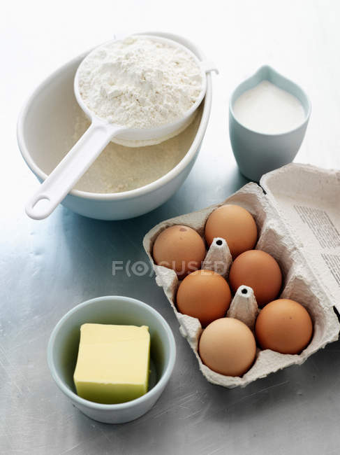 Farina, uova, latte e burro sul tavolo della cucina — Foto stock