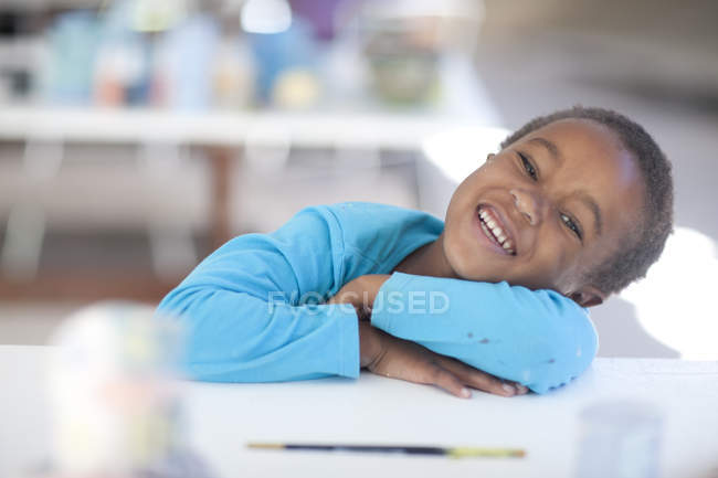 Happy girl arms crossed on table — Stock Photo