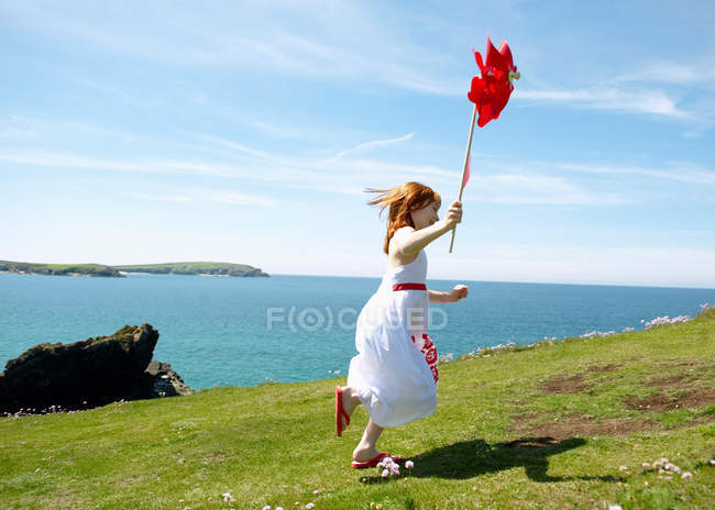 Молодая девушка бежит с ветряной мельницей — стоковое фото