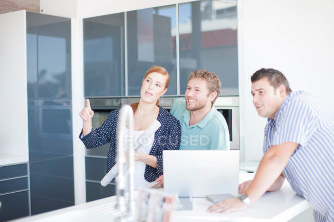 Young couple with salesman in kitchen showroom — Stock Photo