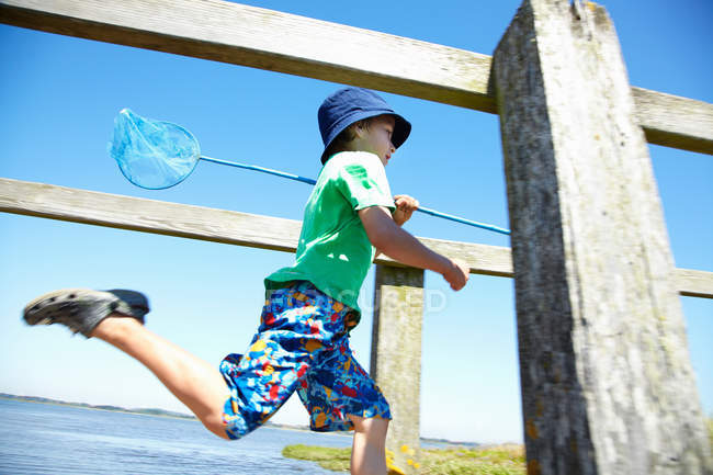 Niño llevando red de pesca en el muelle - foto de stock