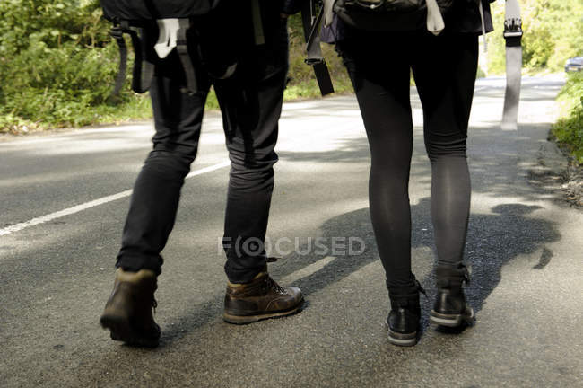 Талія вниз вигляд ззаду молодої пари пішоходів на сільській дорозі — стокове фото