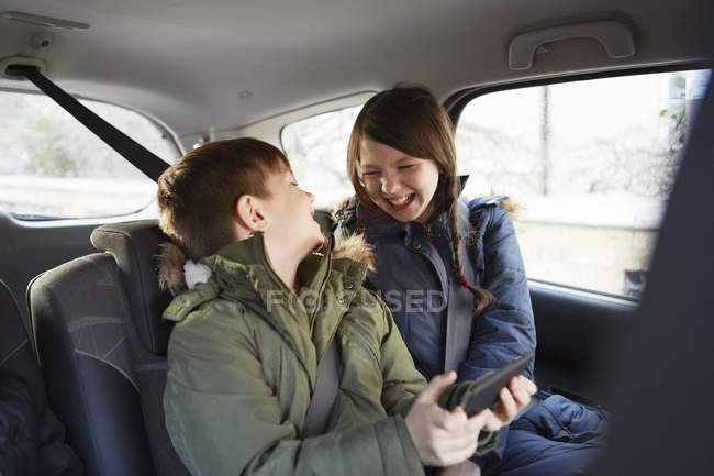 Menino e irmã rindo no banco de trás do carro — Fotografia de Stock