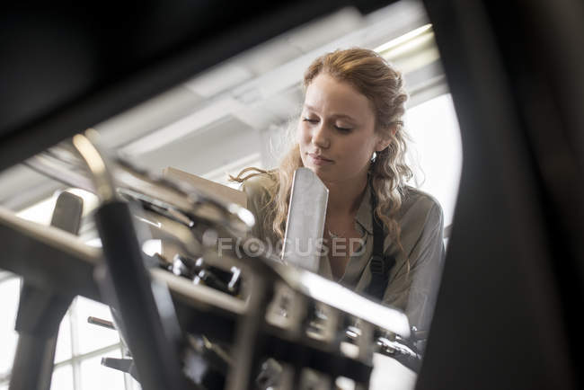 Female printer preparing paper for machine in workshop — Stock Photo
