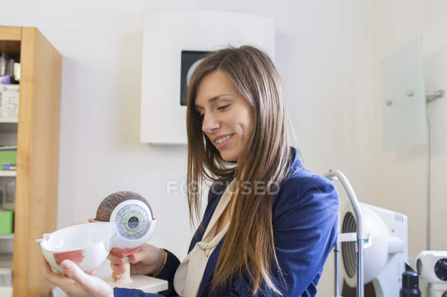 Optician segurando modelo anatômico de globo ocular sorrindo — Fotografia de Stock
