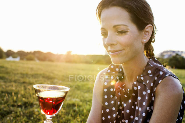 Femme mûre contemplant le vin rouge dans le parc — Photo de stock