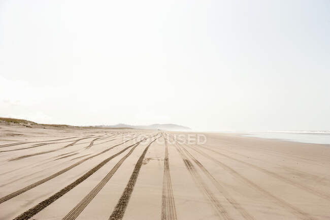 Мальчик на песчаном пляже со следами шин — стоковое фото