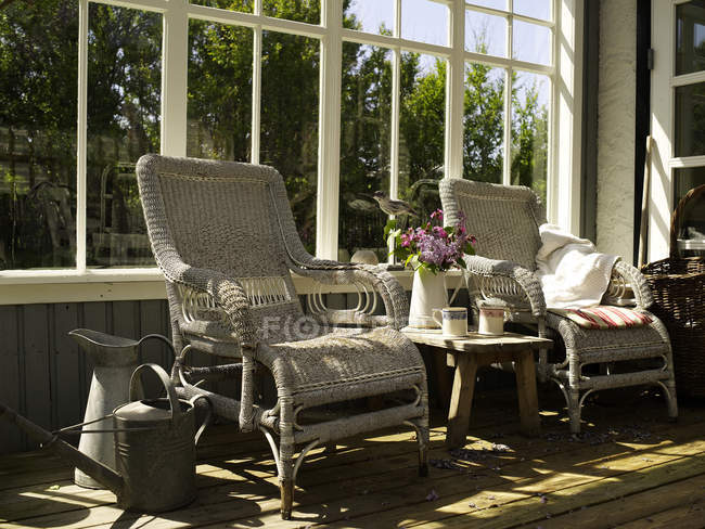 Wicker chairs and side table in sunlit conservatory — Stock Photo