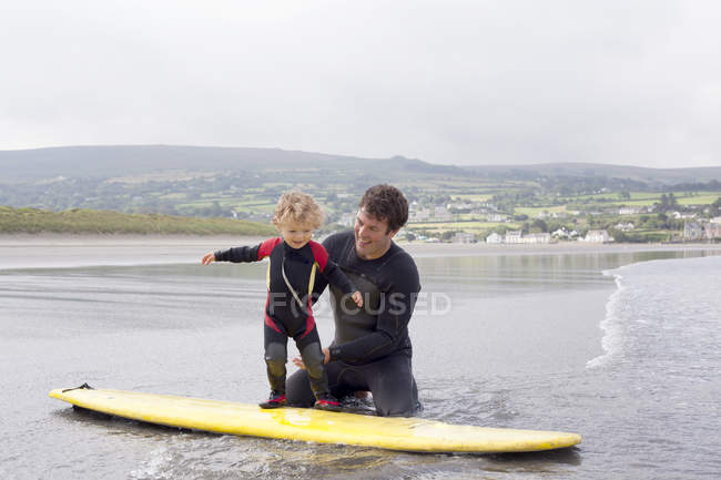 Père enseignant à son fils comment surfer — Photo de stock