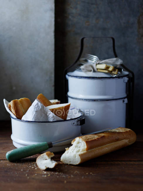 Pan crujiente fresco con cuchillo y tazón en la mesa - foto de stock