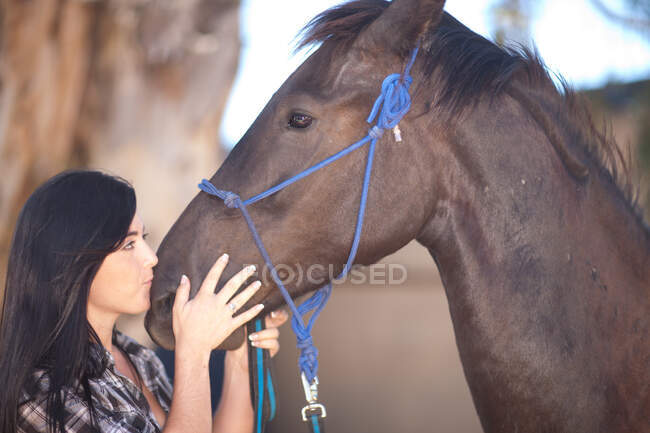 Mujer joven besando la nariz del caballo - foto de stock