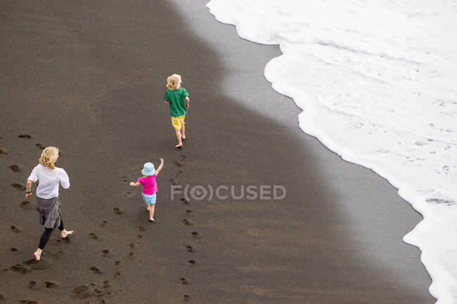 Madre e bambini camminano sulla spiaggia — Foto stock
