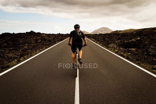 Man cycling in middle of road outdoors — Stock Photo