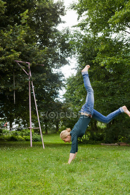 Happy Woman playing in backyard standing on the hands — Stock Photo