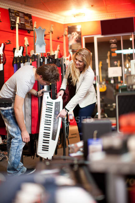 Casal olhando para keytar na loja de música — Fotografia de Stock