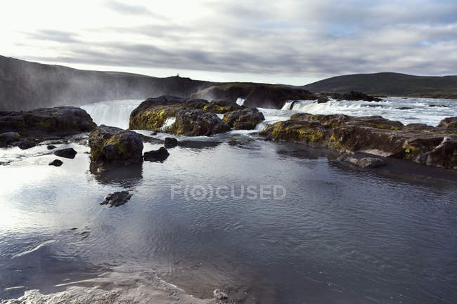 Rocks in waterfalls water and cloudy sky — Stock Photo