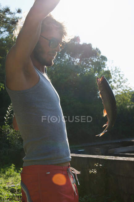 Homem captura peixe no rio — Fotografia de Stock