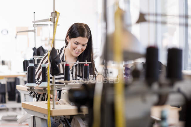 Молодая женщина швея с помощью швейной машинки в мастерской — стоковое фото