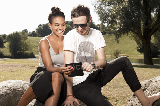 Jeune couple utilisant une tablette numérique dans le parc — Photo de stock
