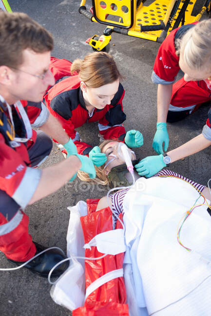 Trois ambulanciers avec patient sur civière portant un masque à oxygène — Photo de stock