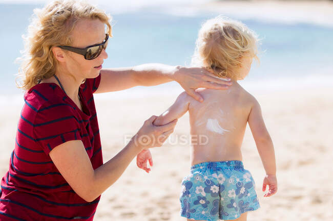 Мать натирает солнцезащитный крем на дочь — стоковое фото